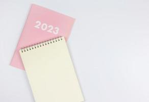 flat lay of blank paper note book on pink diary 2023 on white background. photo