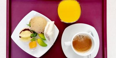 top view photo of a breakfast set in a dark purple tray with sweets, orange juice and hot coffee