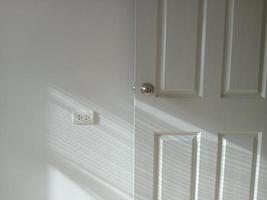 A shot of light and shadow in a white room Light enters to the left through a niche curtain, hitting the room's walls and doors. photo