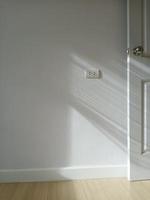 A vertical shot of a room playing with light and shadow coming in from the left window. It hits the walls and the light-colored doors. photo