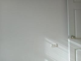 una fotografía de una habitación jugando con la luz y la sombra que brilla a través de la ventana izquierda. golpea las paredes y las puertas de color claro. foto