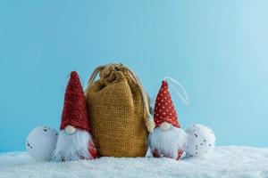 Christmas or winter composition. Two gnomes with a bag of gifts in the snow. photo