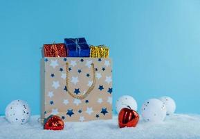 A paper bag filled with gifts stands in the snow. Christmas decorations. photo