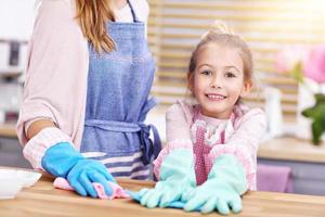 Little girl and her mom in aprons cleaning the kitchen photo