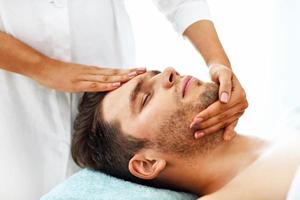 hombre guapo con masaje en el salón de spa foto