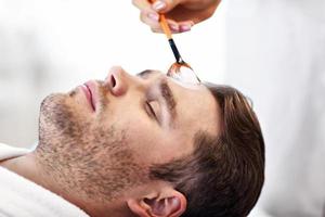 Handsome man having facial in spa salon photo