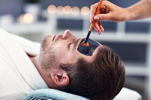 Handsome man having facial in spa salon photo