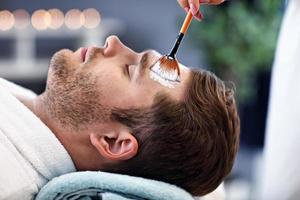 Handsome man having facial in spa salon photo