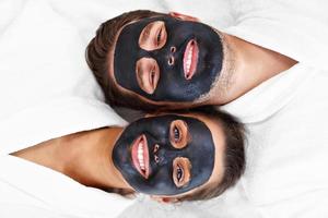 Happy couple having facial in spa salon photo