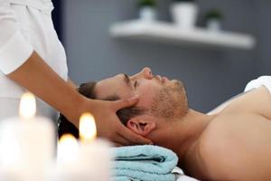 hombre guapo con masaje en el salón de spa foto