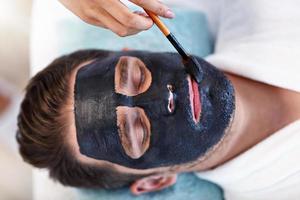 Handsome man having facial in spa salon photo