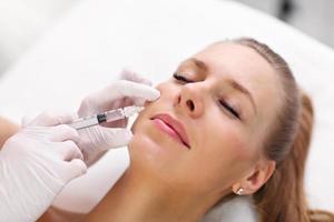 Close up of hands of cosmetologist making botox injection in female lips photo