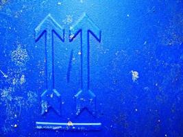Abstract grunge write arrow pointing up, blue tank backdrop with spots cracks. Dot rough surface nameplate. photo