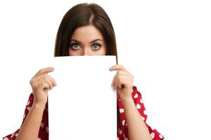 Shocked girl covers her face with sheet of paper isolated on white photo