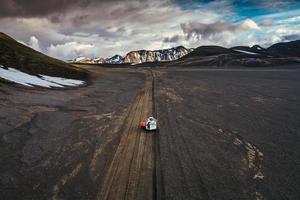 Road trip with tourist 4x4 vehicle car parked on volcanic desert with crater on dirt road in Landmannalaugar at Icelandic Highlands photo
