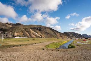 View of hiker tents, 4x4 vehicle camping surrounded icelandic volcanic mountain and river in summer at central of iceland photo