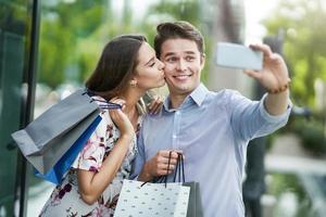 Portrait of happy couple with shopping bags in city smiling and huging. photo