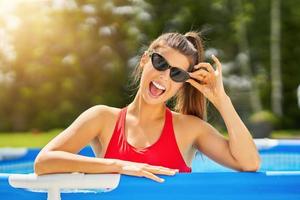 Close up view of attractive woman relaxing on swimming pool in the backyard photo