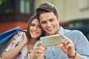 Portrait of happy couple with shopping bags in city smiling and huging. photo