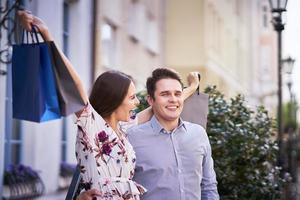 Portrait of happy couple with shopping bags in city smiling and huging. photo