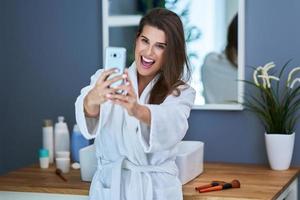 hermosa mujer morena con teléfono inteligente en el baño foto