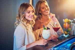 dos amigas tomando bebidas en el bar foto