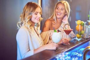 dos amigas tomando bebidas en el bar foto