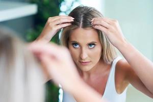 Happy woman brushing hair in bathroom having problem with hair loss photo
