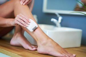 Beautiful woman shaving legs in the bathroom photo