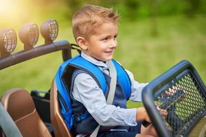 School boy driving kids car with backpack photo