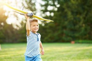 niño feliz de 3 años divirtiéndose jugando con un gran avión al aire libre foto