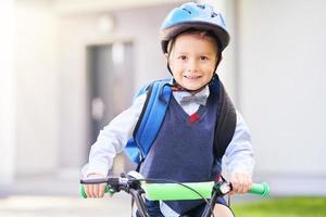 colegial en casco de seguridad montando bicicleta con mochila foto