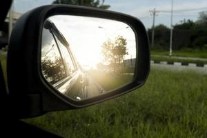 Mirror wing of gray car on the road with many car in traffic jam. In the rush hours and island of green grass. photo