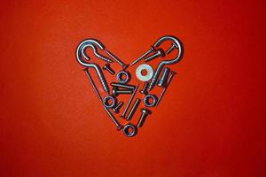 Bolts, nuts, hex and other construction tools laid out in a heart shape, Valentines day postcard, banner, wallpaper, cover design, holiday concept. Flat lay, top view photo