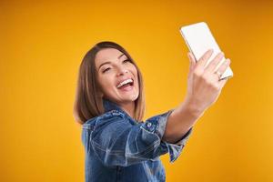 Close up of woman in denim jacket with smartphone over yellow background photo