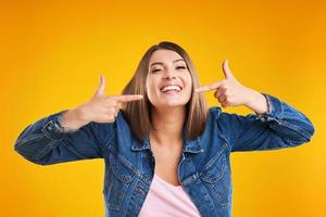 Close up of woman in denim jacket looking at camera over yellow background photo