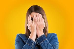 Unhappy woman in denim jacket over yellow background photo