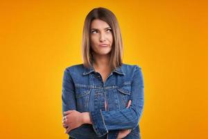 Unhappy woman in denim jacket over yellow background photo