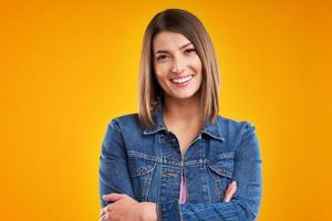 primer plano de una mujer con chaqueta vaquera mirando a la cámara sobre un fondo amarillo foto