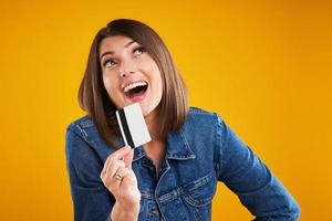 Close up of woman in denim jacket with shopping bags over yellow background photo