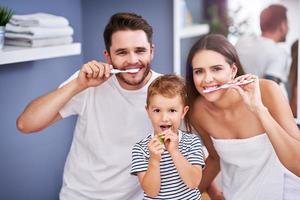 Portrait of happy family brushing teeth in the bathroom photo