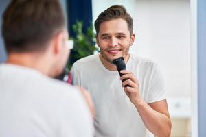 Portrait of adult man shaving in the bathroom photo