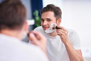 Portrait of adult man shaving in the bathroom photo