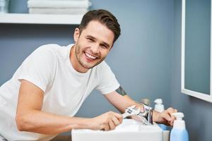 Portrait of adult man fixing sink in the bathroom photo