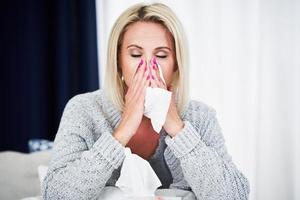 Adult woman feeling unewll with runny nose at home
