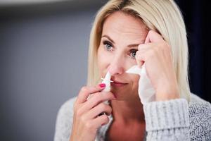 Adult woman feeling unewll with runny nose at home photo