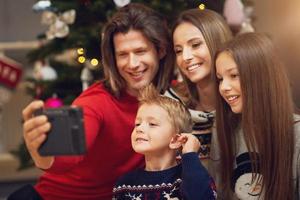 Beautiful family celebrating Christmas at home and taking instant pictures photo