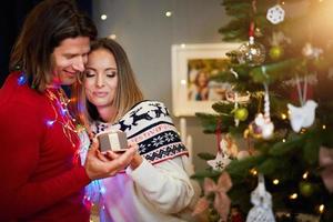 hermosa pareja adulta con presente sobre el árbol de navidad foto