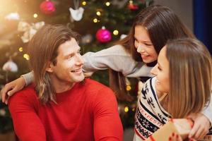 Beautiful family with presents over Christmas tree photo