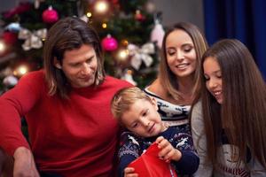 hermosa familia con regalos sobre el árbol de navidad foto